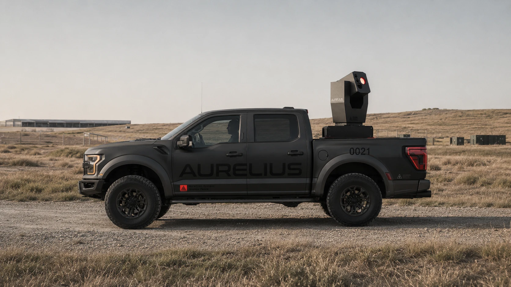Visual concept photograph: side profile of a matte black Aurelius-marked Ford F-150 on open grassland carrying a compact Archimedes system on the bed.